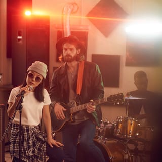 Een band in een studio: zangeres, gitarist en drummer
